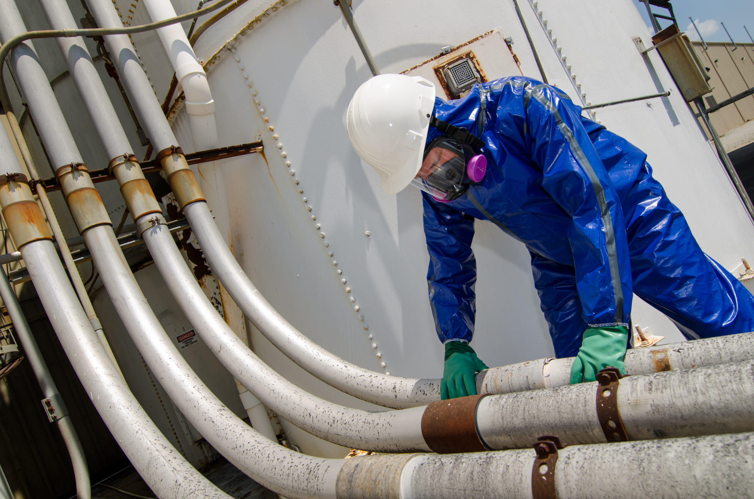 Person inspecting industrial pipes in protective gear.